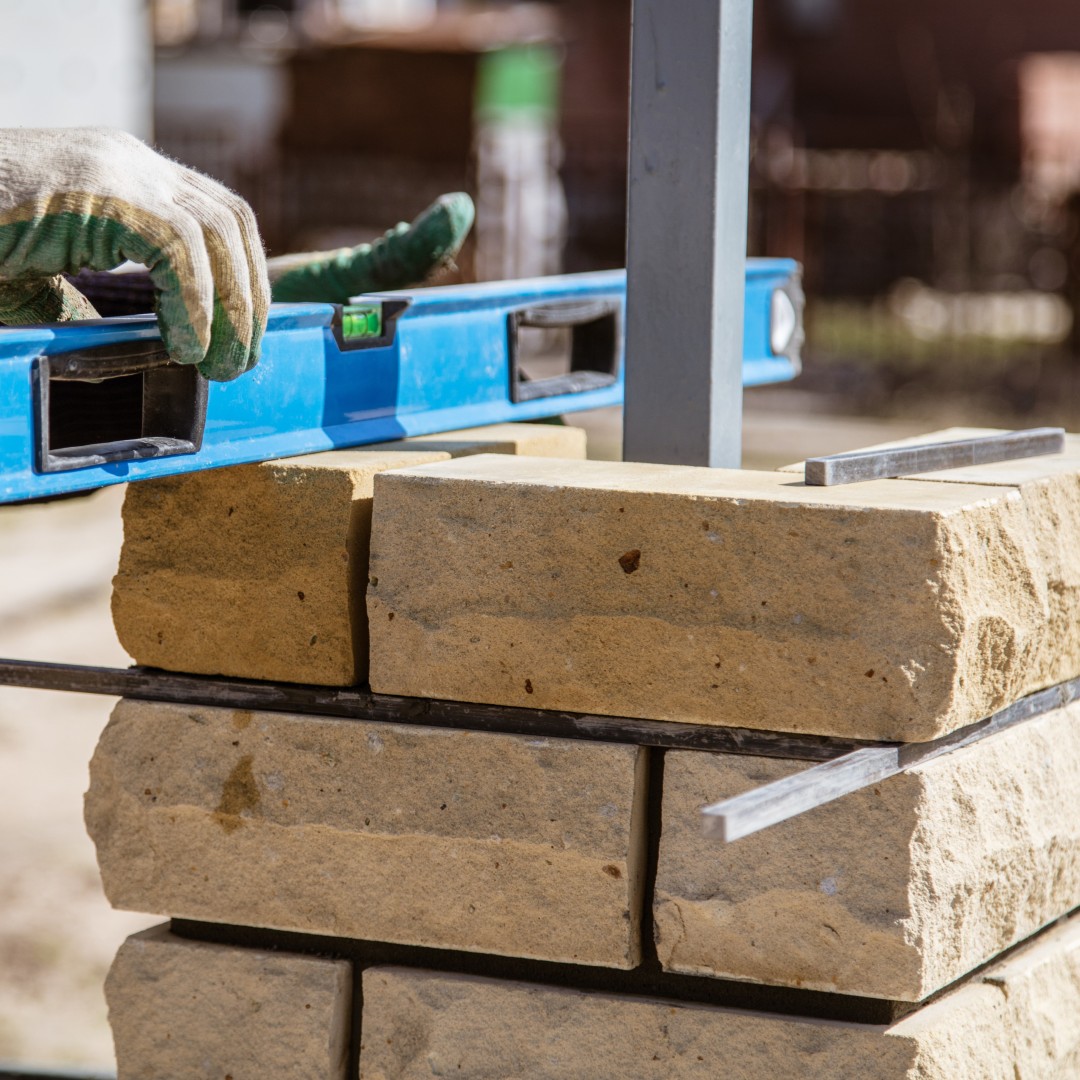 The worker is laying bricks on the fence